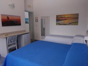 1 dormitorio con cama azul y escritorio en Bed and breakfast Delfino Blu, en Torre Vado
