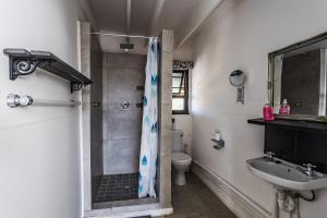 uma casa de banho com um chuveiro, um lavatório e um WC. em Arch Cabins Self Catering Homes Storms River em Stormsrivier