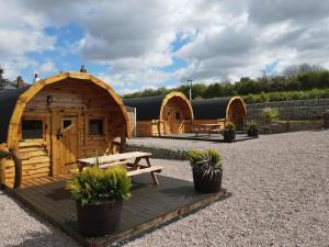 Un grupo de cabañas de madera con plantas en macetas en el frente. en The Plough and Harrow Tilmanstone, en Deal 5 fotos más