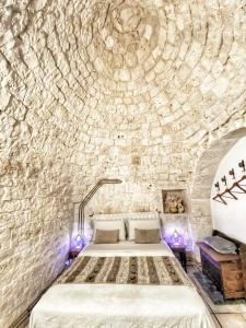 a bedroom with a bed in a stone wall at Trulli Caroli in Locorotondo