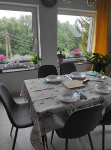ein Esszimmer mit einem Tisch, Stühlen und einem Fenster in der Unterkunft Porębana Osada in Długopole-Zdrój