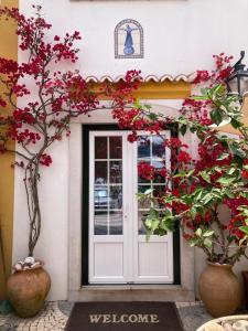 une porte menant à un bâtiment avec des fleurs rouges dans l'établissement Casa da Nazaré, à Portinho da Arrábida