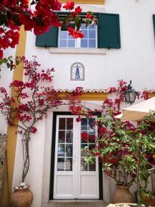 a house with red flowers in front of a door at Casa da Nazaré in Portinho da Arrábida