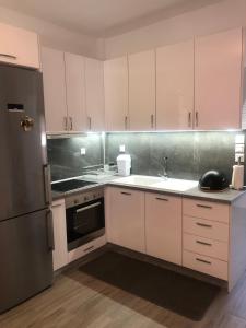 a kitchen with white cabinets and a stainless steel refrigerator at TASOS PARADISE in Polychrono