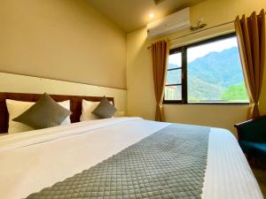 a bedroom with a large bed with a large window at Tapovan New Residency By FTP Hotels in Rishīkesh