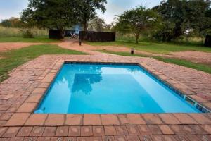 una piscina azul en un patio de ladrillo en 23 Zebula - 4 Bedroom 14 Sleeper Home, en Mabula