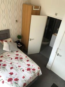 a bedroom with a bed with red flowers on it at Cosy Studio Apartment - Blackheath, Greenwich in London