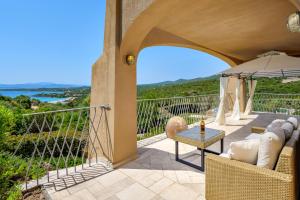patio con tavolo, sedie e ombrellone di Appartamento Eleganza - SHERDENIA Luxury Apartments a Marinella