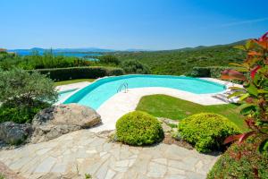 una piscina in un cortile con cespugli e alberi di Appartamento Eleganza - SHERDENIA Luxury Apartments a Marinella