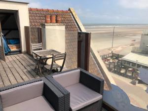 a balcony with a table and a chair and the beach at Villa ALOHA in Bray-Dunes