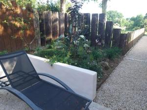 een zwarte stoel naast een plantenbak in een tuin bij Studio meublé avec terrasse axe Rennes Saint Malo in La Baussaine