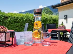 una botella de aceite y dos vasos en una mesa. en Haus Tirol, en Brixen im Thale