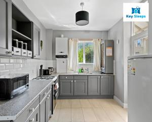a kitchen with gray cabinets and a white refrigerator at Spacious House By Keysleeps Short Lets Canterbury With Garden Contractors Leisure in Kent