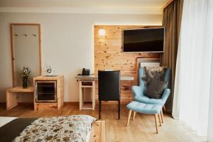 a bedroom with a bed and a chair and a desk at Wellness Natur Resort Gut Edermann in Teisendorf
