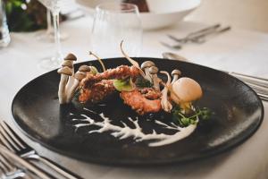 a black plate of food with mushrooms on a table at Wiesenhof Gardenresort in San Leonardo in Passiria