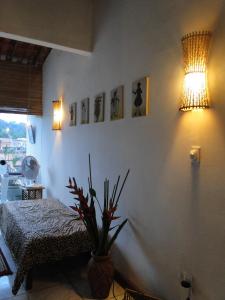 - une chambre avec un lit et une plante en pot dans l'établissement Casa de Vidro, à Itacaré