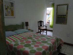 a bedroom with a bed and a chair and a window at Casa de Vidro in Itacaré