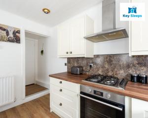 a kitchen with white cabinets and a stove at NEW Four Bedroom House By Keysleeps Short Lets Workington Contractor Leisure Beach Location Lake District in Siddick