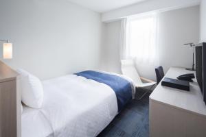 Hotel Folkloro Sanrikukamaishi في Kamaishi: غرفة نوم بسرير ومكتب مع تلفزيون