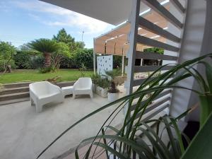 a patio with two white chairs and plants at Casa da Marion in Letojanni