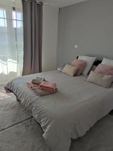 Una gran cama blanca con almohadas rosas. en Chambre Ruaudin, en Ruaudin