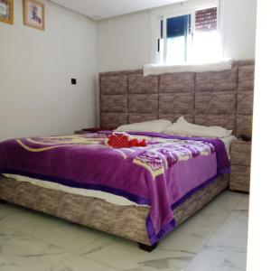 a bed with a purple blanket on top of it at Qamar's guests 3 in Al Hoceïma