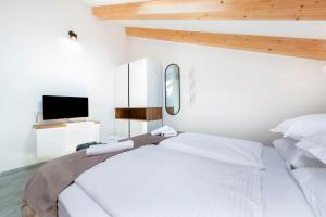 a white bedroom with a bed and a tv at Boutique Residence Arion in Rovinj