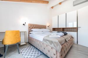 a bedroom with a large bed and a yellow chair at Boutique Residence Arion in Rovinj