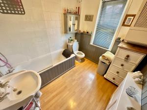 a bathroom with a tub and a toilet and a sink at Garden Cottage - 3 Bedroom Close to Town and Beach in Bournemouth
