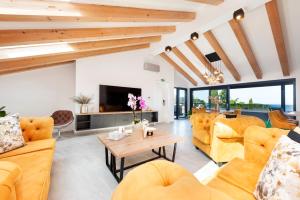 a living room with yellow furniture and a tv at Boutique Residence Arion in Rovinj