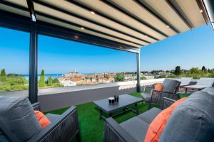 a balcony with couches and tables and a large window at Boutique Residence Arion in Rovinj