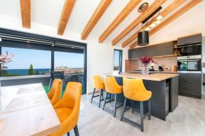 a kitchen with a large island with yellow chairs at Boutique Residence Arion in Rovinj