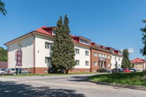 um grande edifício branco com uma árvore em frente em SISI Pension em Púchov