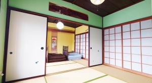 a room with japanese doors and a bedroom at ゲストハウス 編湊 in Nakaminato