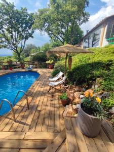 une terrasse en bois avec une piscine et un parasol dans l'établissement La lyalis, à Aiguines