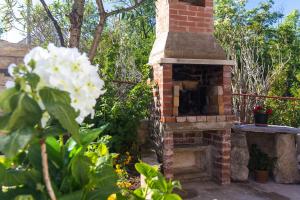 un forno in mattoni esterno in un giardino con un fiore bianco di Apartments House Risika a Risika