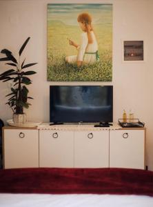 um quarto com uma televisão e um quadro na parede em Το Σπίτι Της Ευτυχίας στούντιο em Karpenision