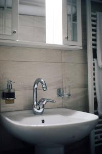 lavabo blanco en el baño con espejo en Το Σπίτι Της Ευτυχίας στούντιο en Karpenision