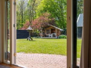 eine offene Tür zu einem Garten mit einem Pavillon in der Unterkunft Family Villa in Forest with shared pool & Wellness in Zeewolde