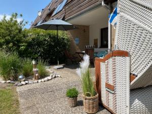 eine Terrasse mit einem Sonnenschirm, einem Tisch und Stühlen in der Unterkunft MEI71 Ferienwohnung Strandlust F in Niendorf