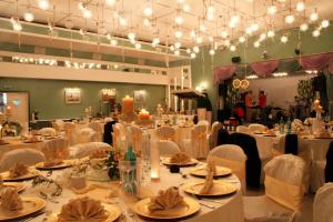 un salón de banquetes con mesas blancas, sillas y luces en Hotel Reifenstein, en Kleinbartloff
