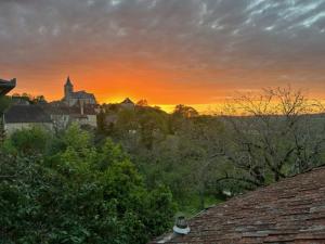 a sunset over a city with a church and trees at La Forge de Béduer in Béduer