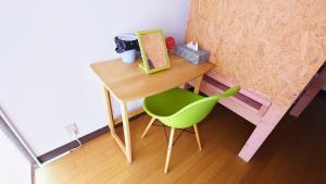a small desk with a green chair in a room at ゲストハウス 編湊 in Nakaminato