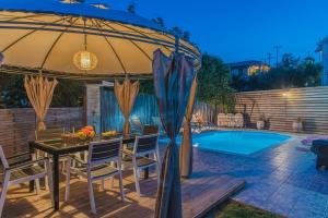 a patio with a table and an umbrella next to a pool at Villa Danae in Laganas