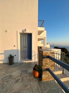 une maison avec une porte bleue et un balcon dans l'établissement Aegean Mirror, Andros, à Apróvaton