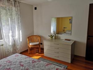 a bedroom with a dresser and a mirror and a chair at Casa Il Glicine in Baceno