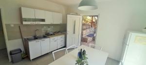 a kitchen with white cabinets and a table and a sink at Apartman Bonkovic in Gdinj +35 photos