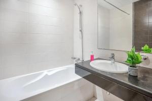 a white bathroom with a sink and a bath tub at PRIME LOCATION 3 Bedroom Beach Front (Side View) in Abu Dhabi