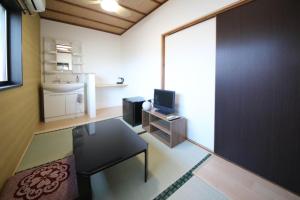 a living room with a table and a tv in a room at さきみや in Goto