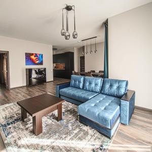 ein Wohnzimmer mit einem blauen Sofa und einem Tisch in der Unterkunft Kintų Perlas in Kintai